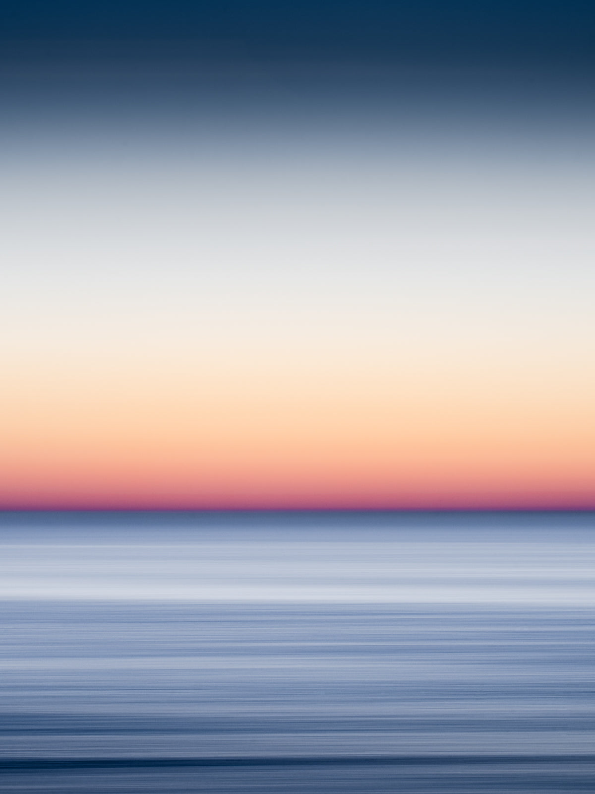 Orange and blue long exposure photograph of a sunset over the north sea. Using the panning technique to give the ocean surface a smooth, soft effect.