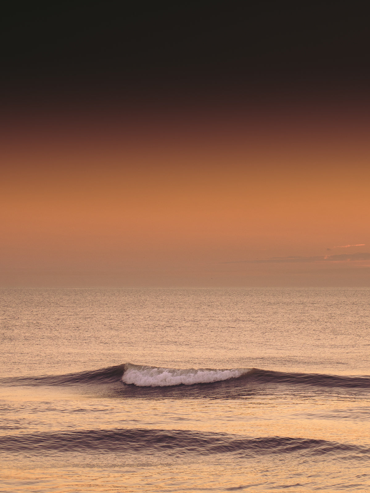 Golden wave breaking softly under a glowing sunset. A serene coastal photo, perfect for sea lovers and elegant interiors.