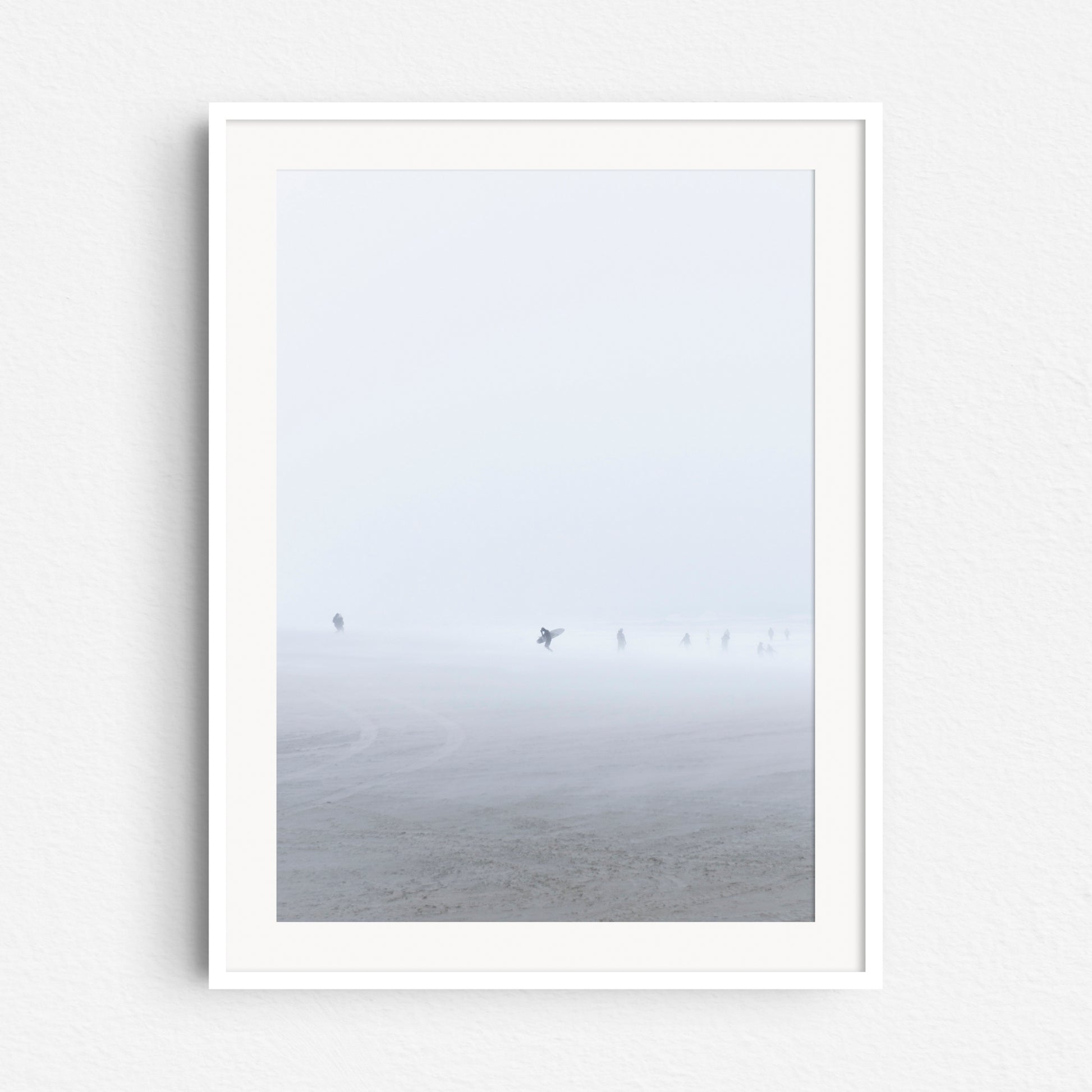 A surfer in a blizzard on the Scheveningen beach, print in a white wooden frame.