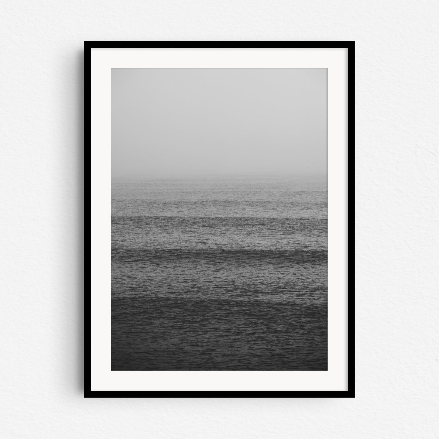 A black and white surf photo for your wall, framed in black wood with a white passe-partout.