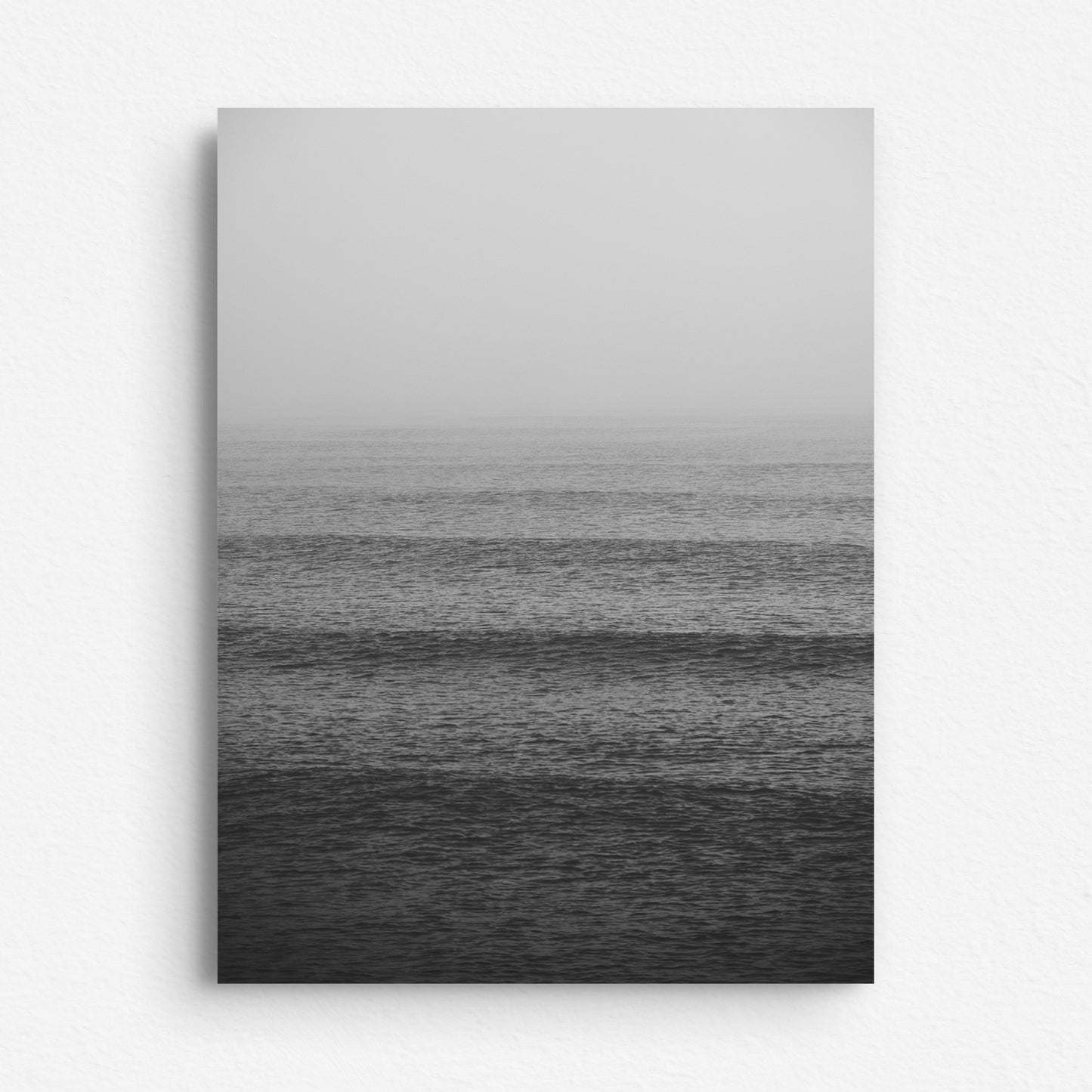 A dibond print of the North Sea water surface in black and white, shades of waves rolling into the coast.