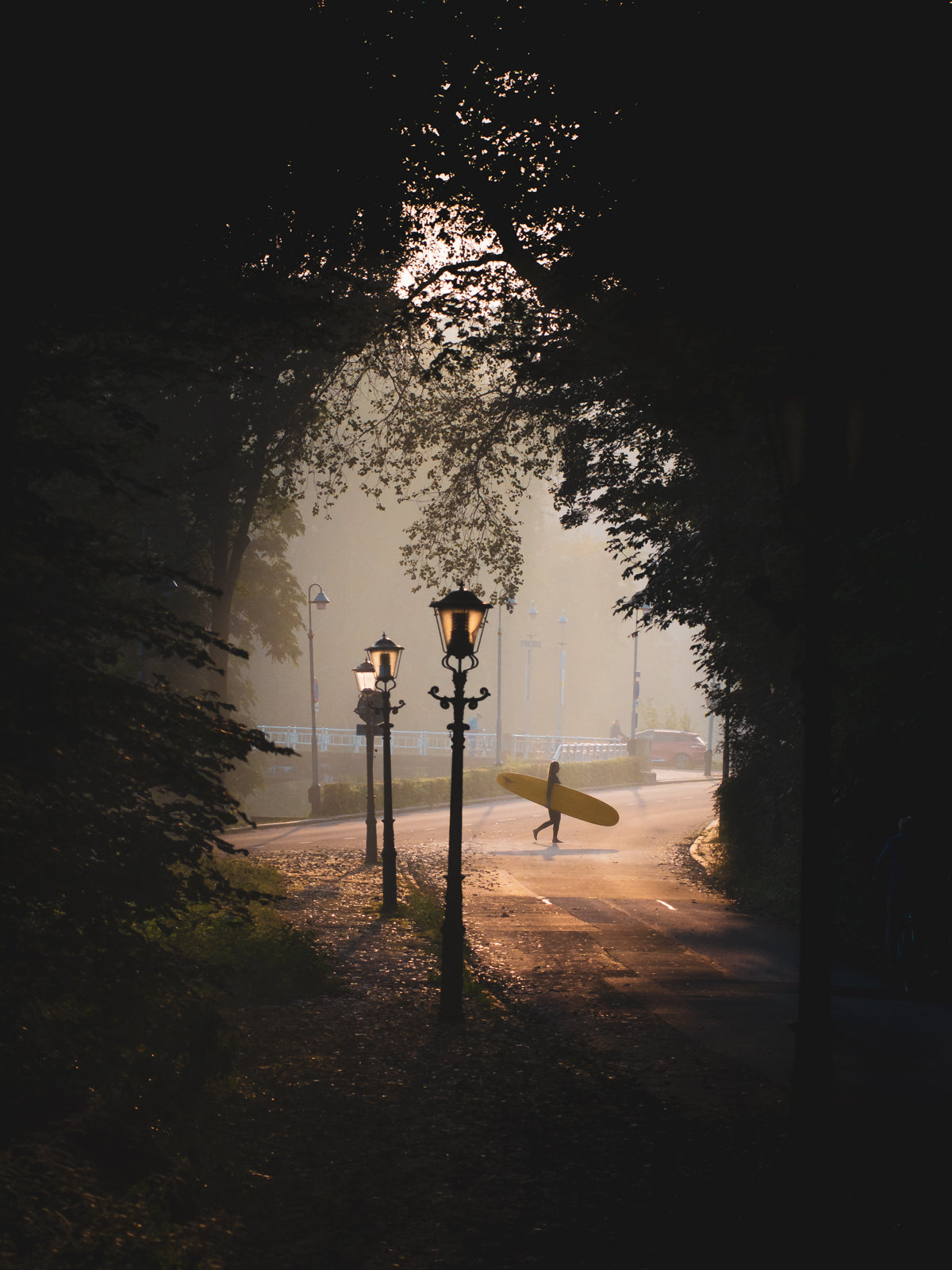 A surfer crosses the road on a misty morning in one of streets of The Hague.