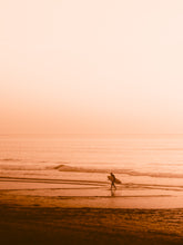 Load image into Gallery viewer, Surfer walking back from a surf session in an orange sunset glow, captured by Jop Hermans.
