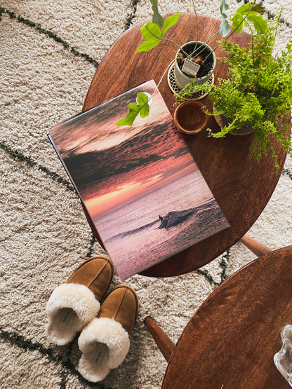 A surf print on a wooden table with warm shoes and healthy green plants next to it.