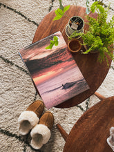 Load image into Gallery viewer, A surf print on a wooden table with warm shoes and healthy green plants next to it.
