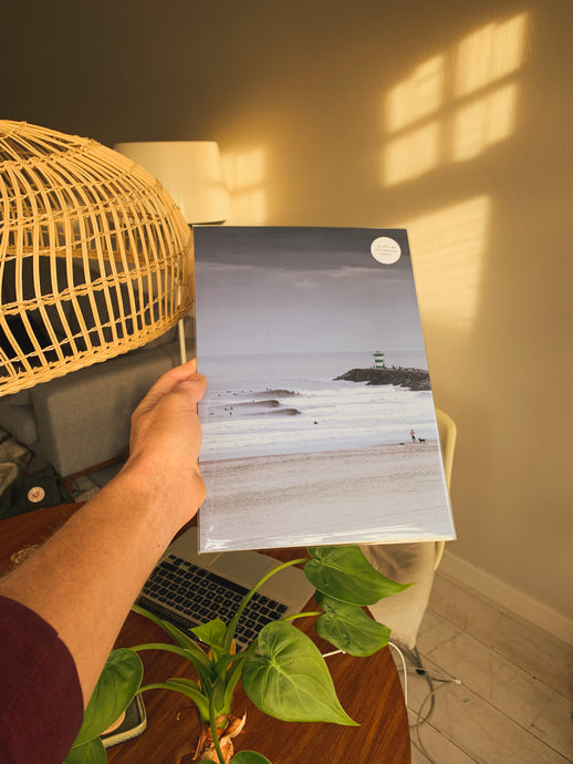 Surfing waves break in a bech in the Hague with the lighthouse visible. A beautiful surf print and gift.