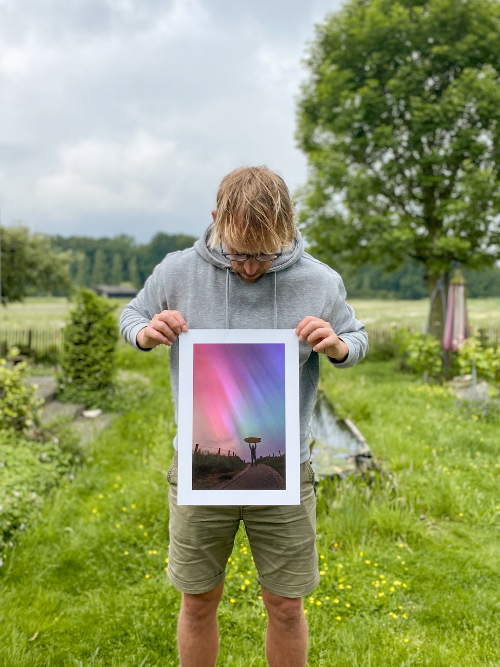 Jop Hermans holding a limited edition photo print in his garden.