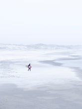 Load image into Gallery viewer, Winter surf photography in Scheveningen where a surfer walks over the snowy beach.
