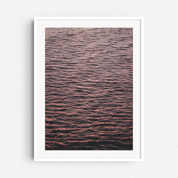 A photograph of the North Sea surface showing endless ripples coloured by the sunset, captured by Jop Hermans.