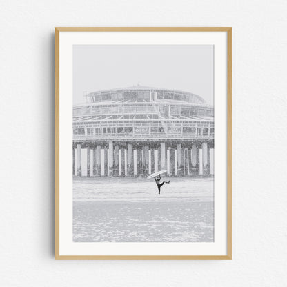 A local The Hague surfer is happy during a surf session in a snow storm, framed in a natural wooden frame.