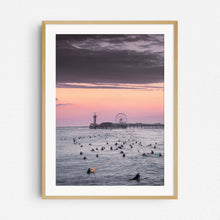 Load image into Gallery viewer, Many surfers in the North Sea, visible as silhouettes. With the Scheveningen pier as a backdrop, framed in natural wood.
