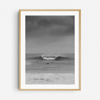 Big wave captured in Scheveningen by Jop Hermans. The black and white print in a natural wooden frame.