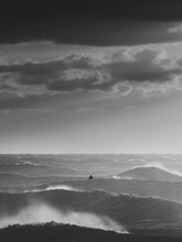 Load image into Gallery viewer, A surfer silhouette sits in between heavy waves in the North Sea.
