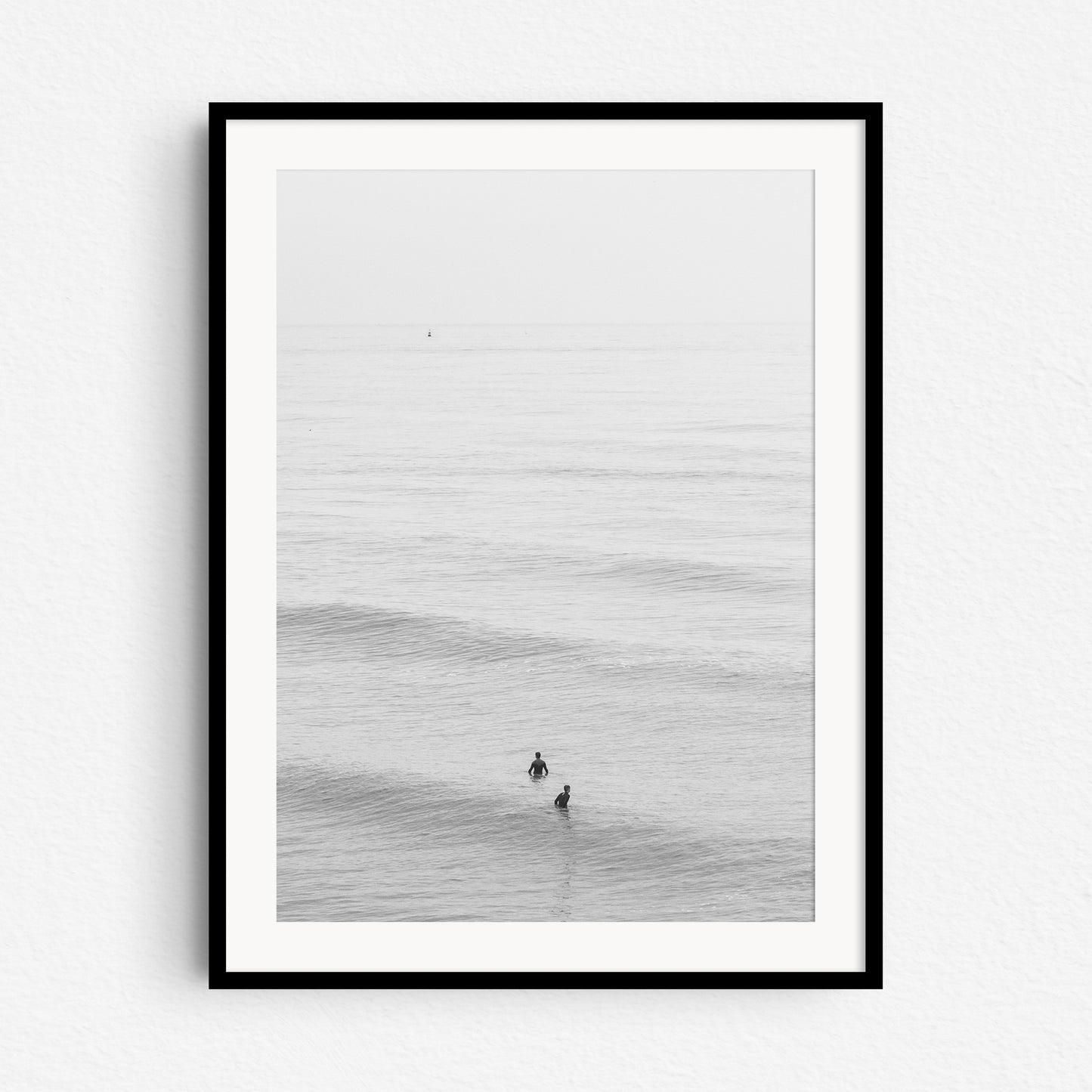 A minimalistic black and white surf photograph, in a black wooden frame.