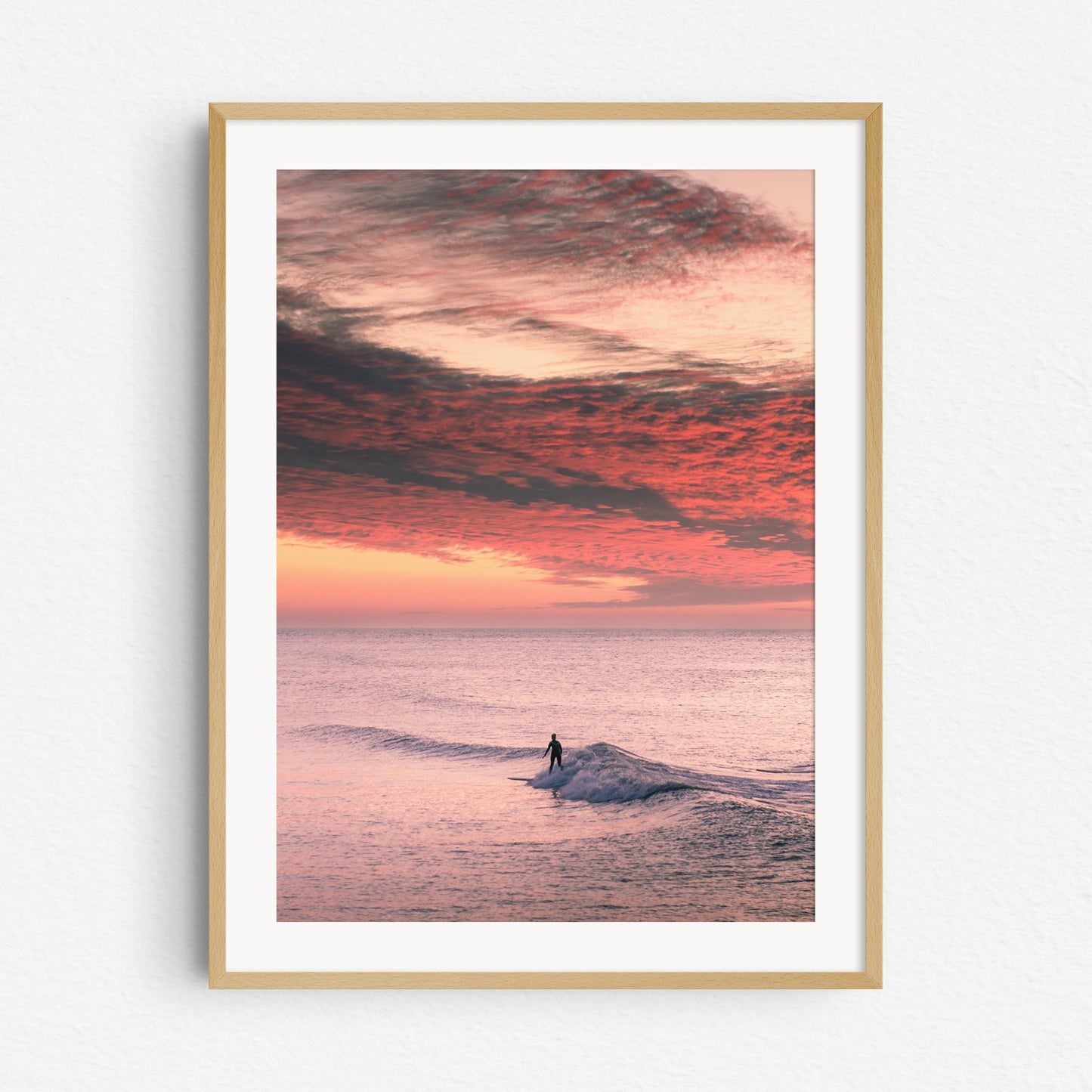 "Sunset Surf" – A serene shot of a female surfer during a vibrant North Sea sunset. Framed in natural wood for a warm, organic touch.