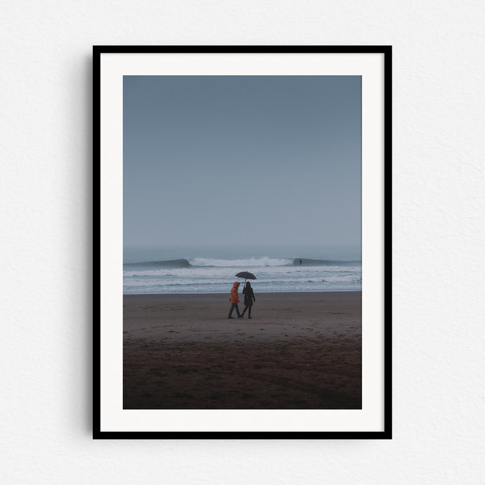 A couple with an umbrella in the rain on the Scheveningen beach, captured by Jop Hermans.