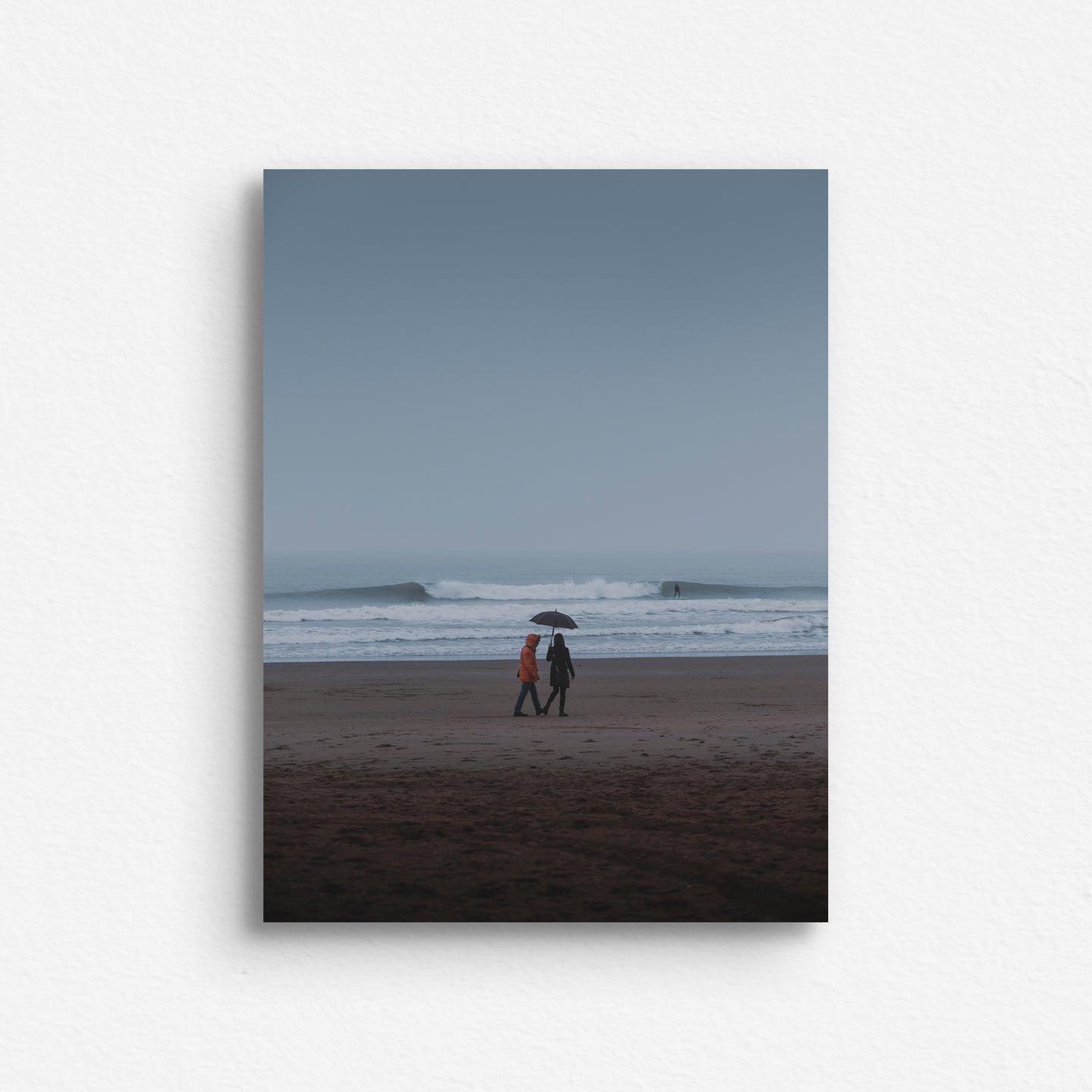 Two people carry an umbrella with a beautiful North Sea wave breaking in the background. Surf artwork printed on aluminum dibond for a sleek look.