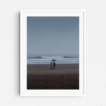 Load image into Gallery viewer, A surfer rides a wave in a rainy landscape. Minimalistic photo art from The Hague, framed in white wood.
