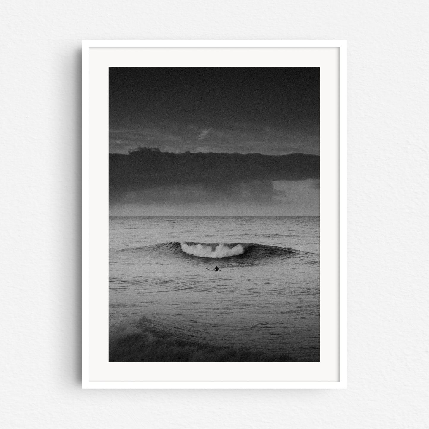 Black and white surf photography at the Scheveningen coast in a white wooden frame.