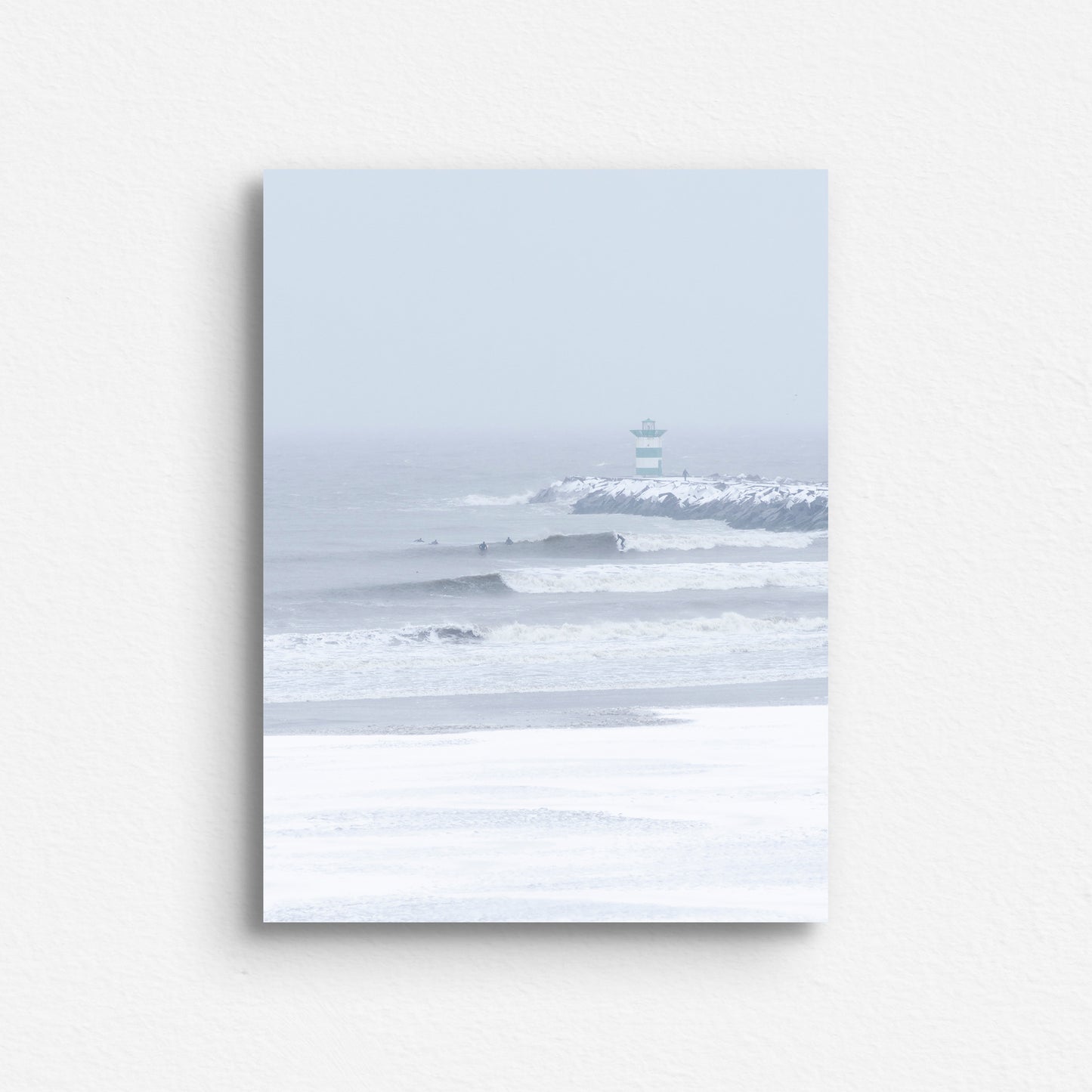 A winter surf shot with big waves and a snowy beach in Scheveningen printed on dibond.