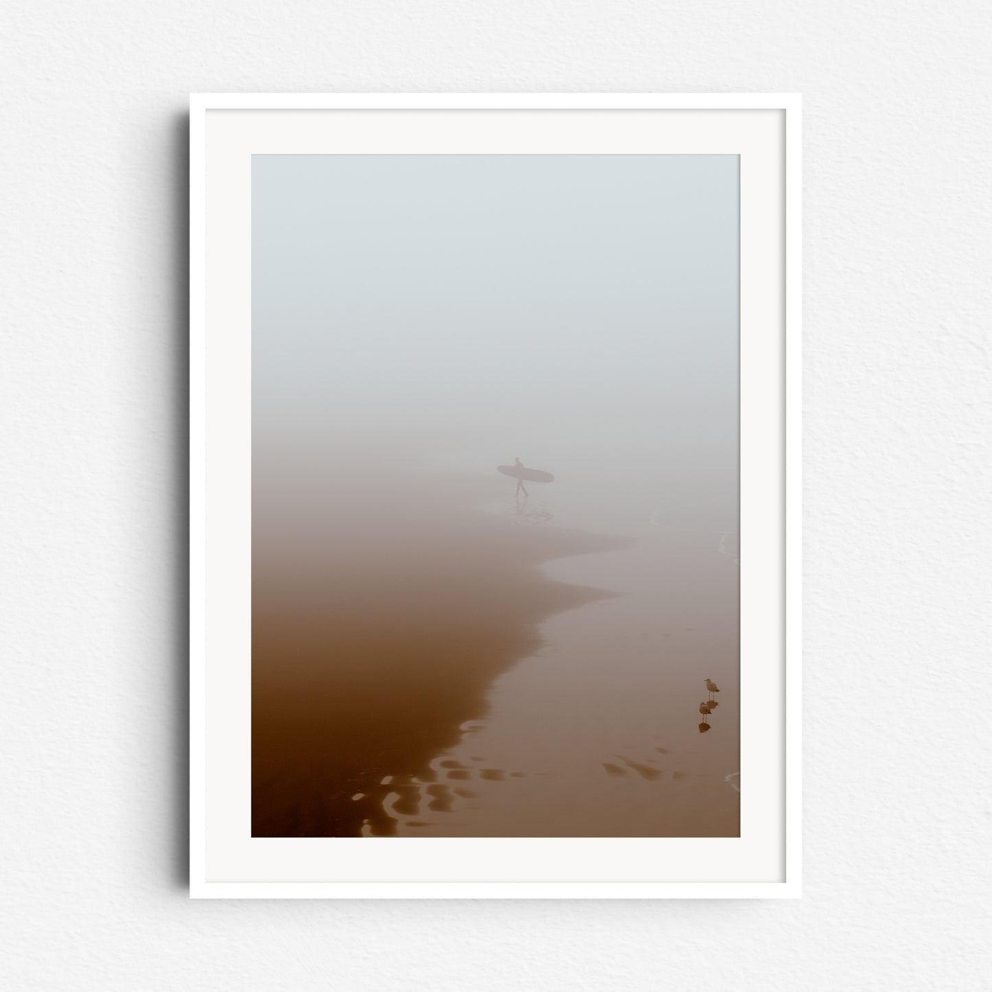 Print in white wooden frame: Calm seascape with a surfer leaving the water in thick fog, framed in white wood for a clean, modern look.