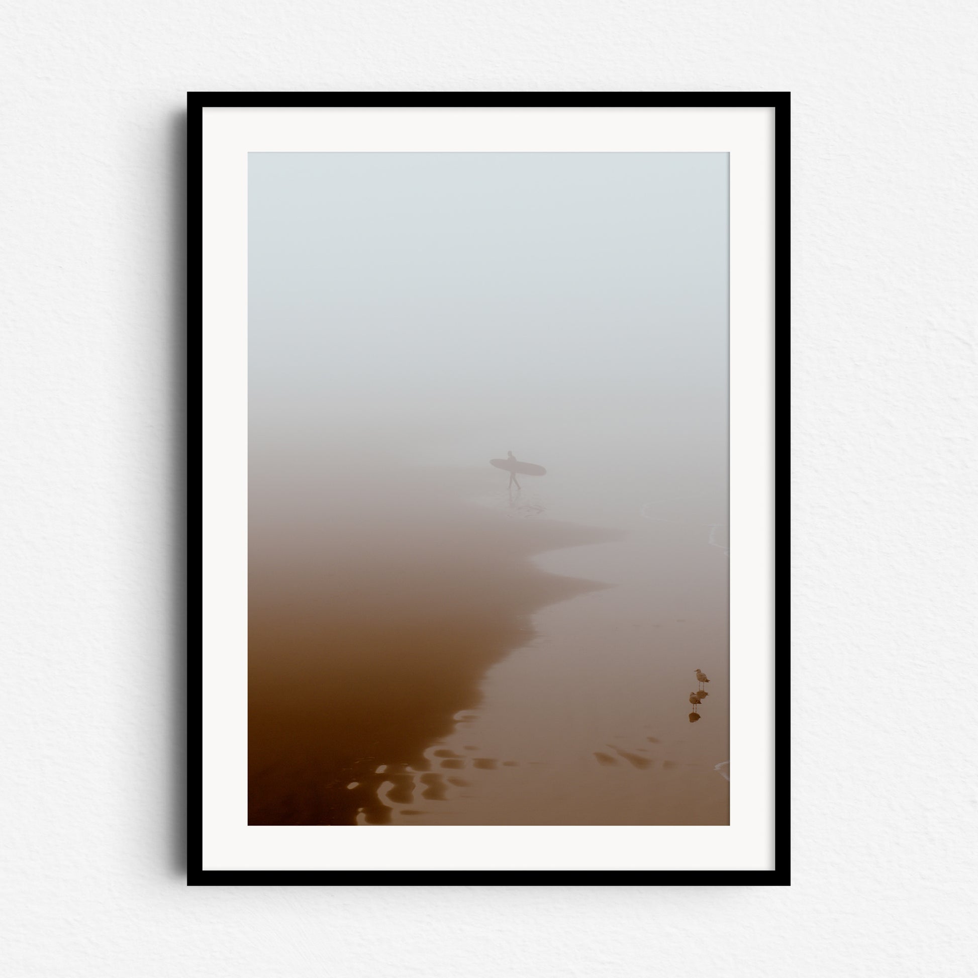 Surfer leaving the water in thick fog, framed in black wood for a dramatic touch to your wall art.