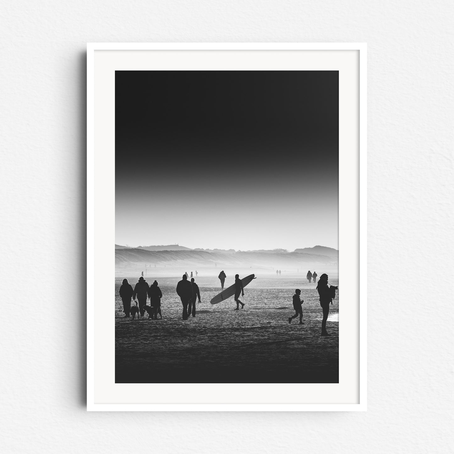 High contrast black and white photo of a beach scene with a longboarder, framed in white wood, perfect for elegant Wall decoration.