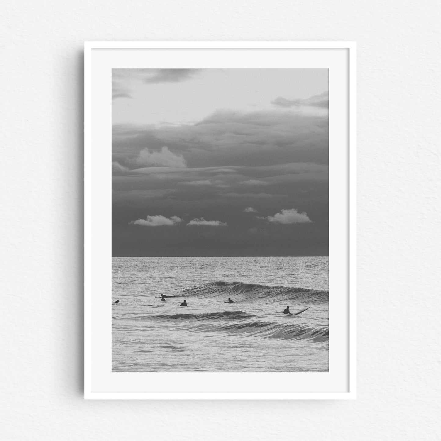 Surfers in the North Sea landscape in a white wooden frame.