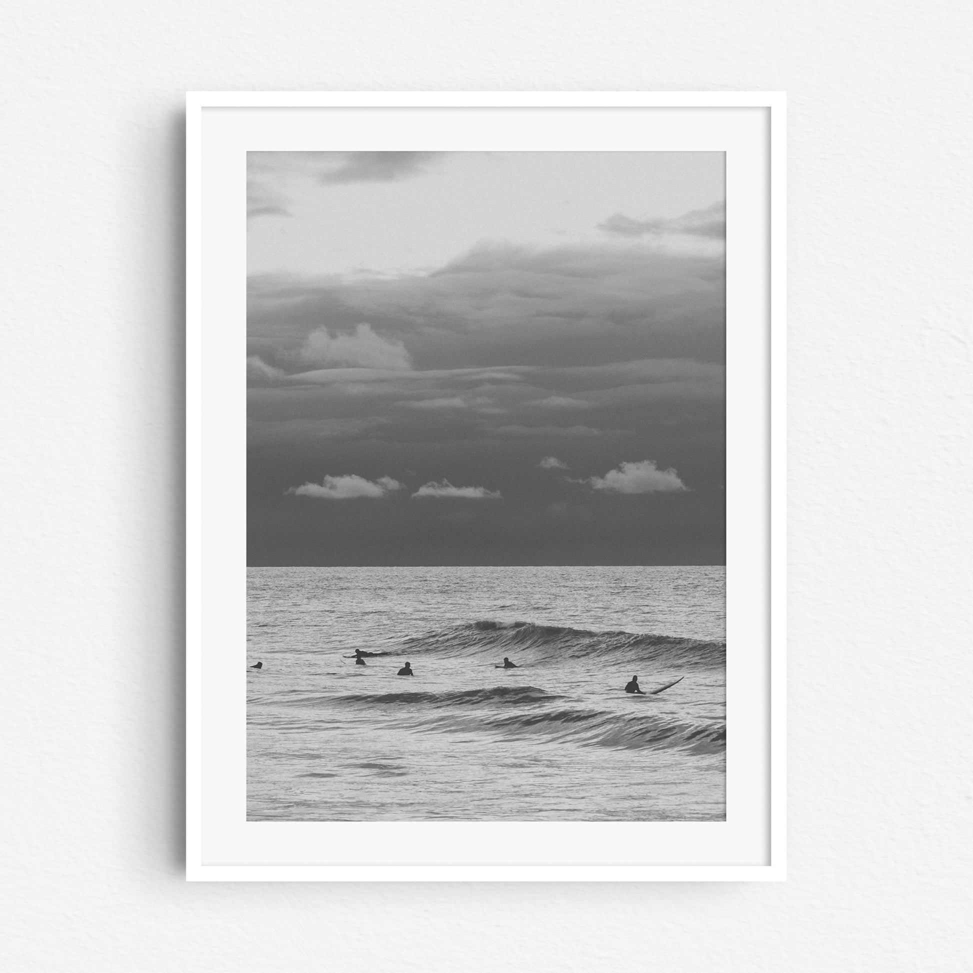 Surfers in the North Sea landscape in a white wooden frame.