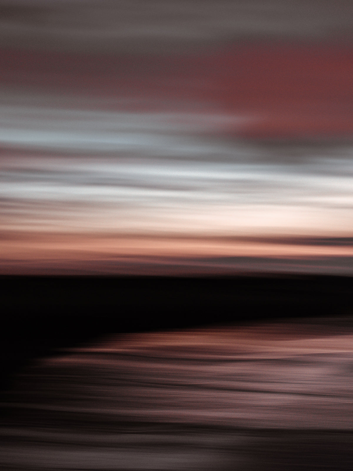 Long exposure minimalis panning photo taken on the beach during sunset in Scheveningen. The sky is has pastel colours.