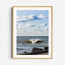 Load image into Gallery viewer, A surfer in The Netherlands near the harbor wall in front of a large breaking wave, framed in natural wood for a relaxed, coastal vibe.
