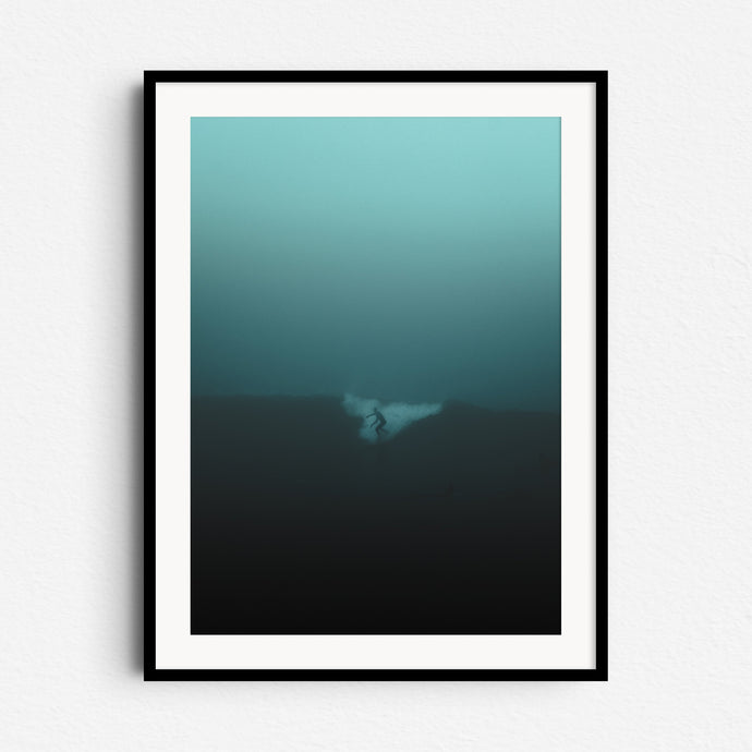 Silhouetted surfer on a misty Scheveningen morning in a turquoise haze. Framed in black wood for a bold, moody wall art piece.