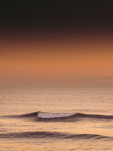 Load image into Gallery viewer, A gentle rolling wave with a golden glow in the air. Shot in Scheveningen - The Netherlands.
