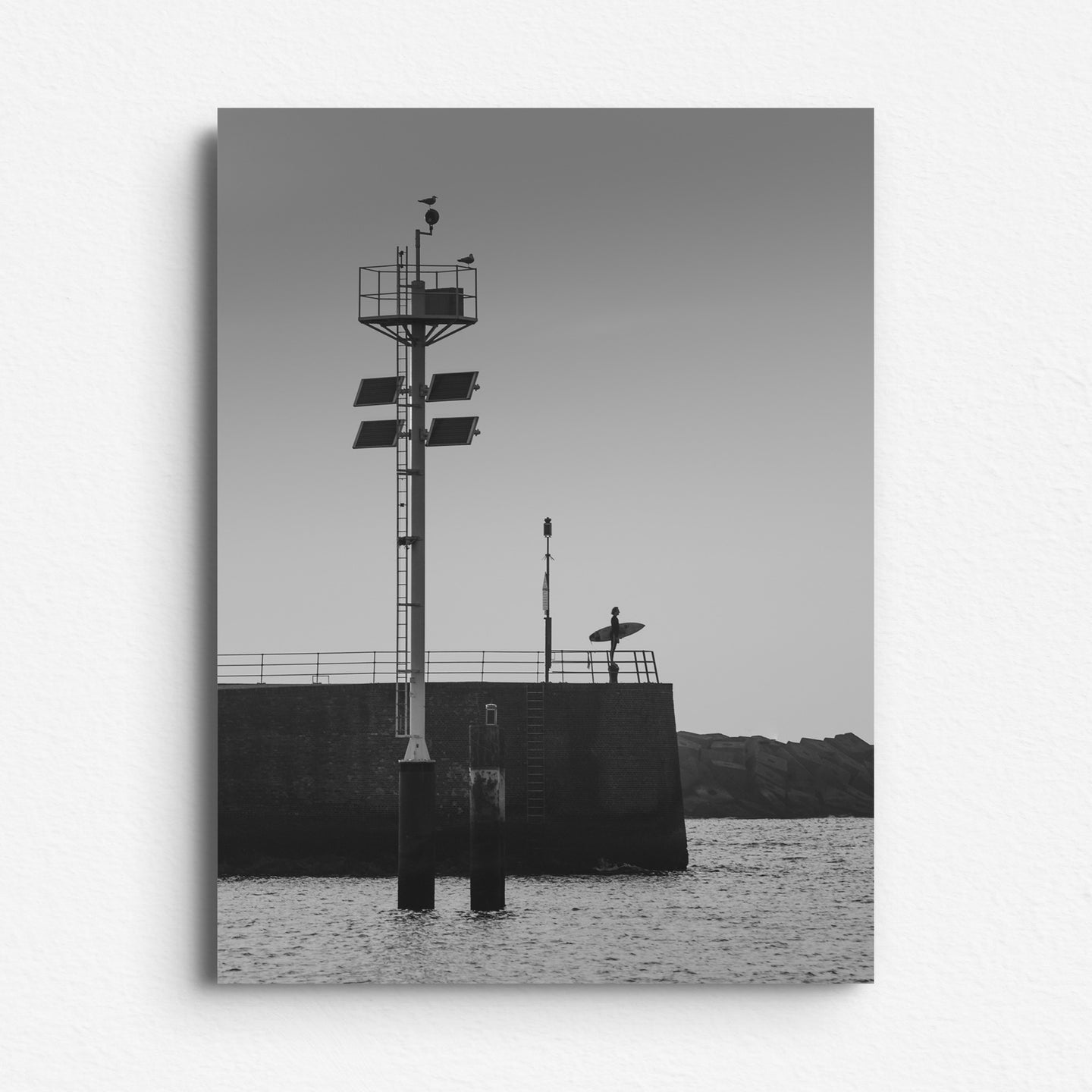 Black and white surfer silhouette in Scheveningen, looking out at sea. Printed on Dibond for a sleek, modern wall art display. A North Sea seascape by Jop Hermans.