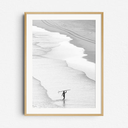 Peaceful black and white image of a surfer walking on the beach in The Hague, framed in natural wood for a warm, organic look. 