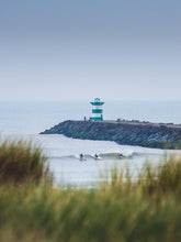 Load image into Gallery viewer, Three surfers on the same wave in Scheveningen, with in the background a lighthouse. Shot from the Scheveningen dunes.
