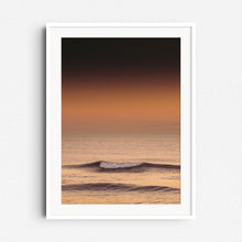 Load image into Gallery viewer, A calm wave crumbles in a golden sunset glow, framed in white wood. Serene photo art for minimalist home decor.
