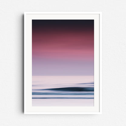 A dreamy photo in Scheveningen of a purple-lit sky, captured with long exposure. Framed in white wood for a serene vibe.