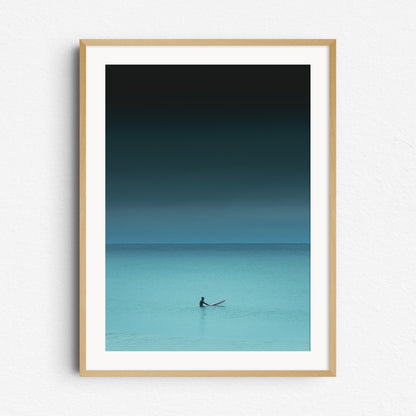 Moody turquoise nature photography of a surfer in the North Sea waiting for a wave. Framed in natural wood, ideal for nature and surf photography lovers. Captured by Jop Hermans