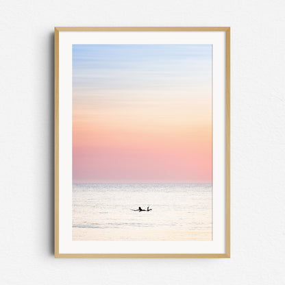 Surfer paddles the North Sea in a peaceful pastel hot summer glow, framed in natural wood for a calming, coastal look. Captured by Jop Hermans