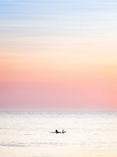 Load image into Gallery viewer, The silhouette of a female surfer paddling in the Dutch North sea, with soft pastel colours in the sky. Surf photography by Jop Hermans
