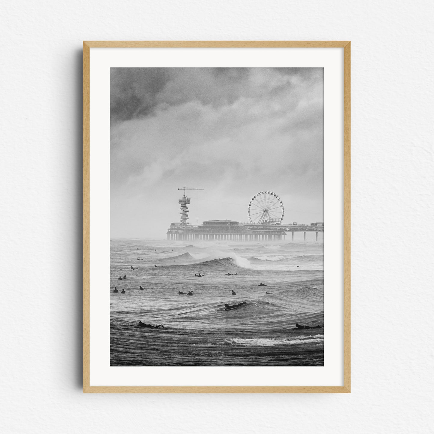 Classic Dutch surf scene in black and white. With surfers, the iconic Scheveningen pier and moody skies, framed in natural wood for a balanced, earthy display.