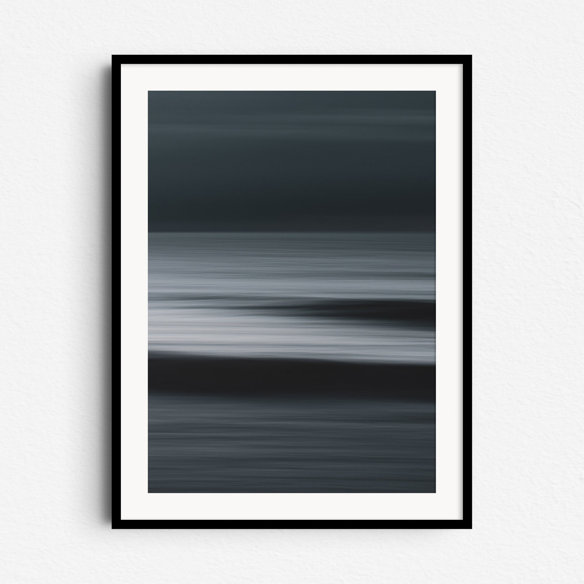 "Shades" – dark abstract North Sea photo with strong contrasts. Framed in black wood for bold, dramatic wall decoration.