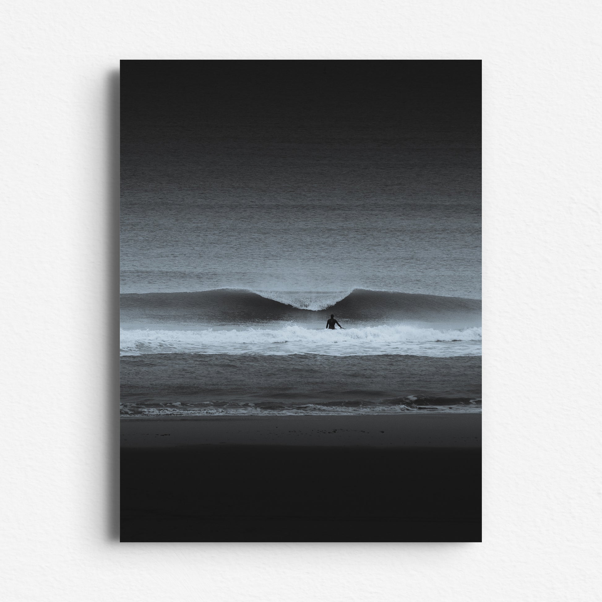 A striking black-and-white seascape with a surfer and crashing wave. Printed on Dibond. The Hague artwork.