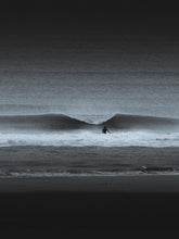 Load image into Gallery viewer, A moody, surreal black-and-white photo of a surfer facing a breaking wave on a beach in Scheveningen. A dramatic wall art piece.
