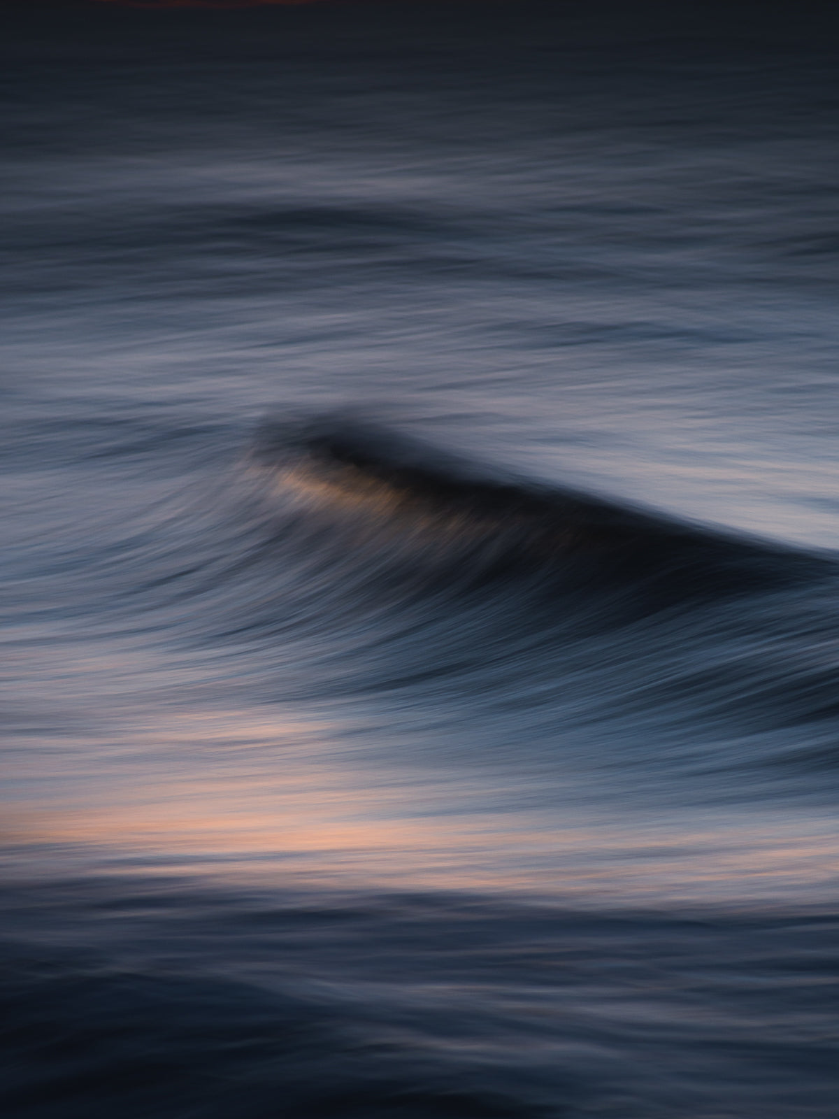 Abstract photograph of a breaking wave in Scheveningen - The Hague. Blue tones and motion blur give a soft effect.