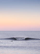 Load image into Gallery viewer, Pastel tones in the sky with a beautiful clean wave breaking, with just one surfer is paddling out towards it in a calm north sea.
