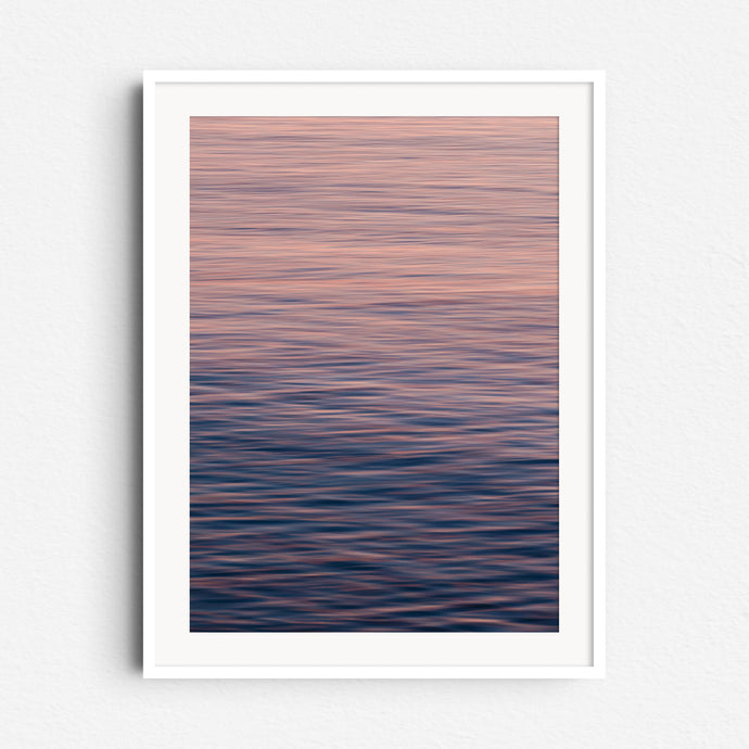 Pastel blues and oranges create a serene North Sea photo. Soft movement, framed in white wood for a calming, modern look.