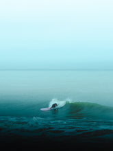 Load image into Gallery viewer, A surfer in The Netherlands surfs a wave on a pink surfboard in turquoise water.
