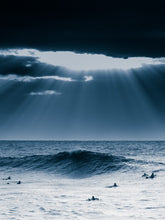 Load image into Gallery viewer, Dramatic surf landscape with sunlight through clouds, surfers, and deep blues. A striking North Sea photo for your wall.
